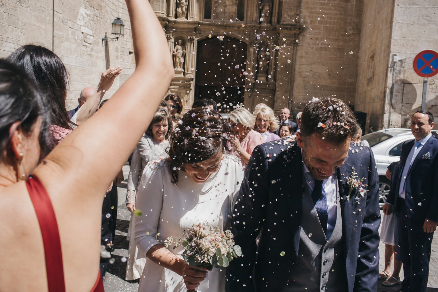 Invitados lanzando confeti a los recién casados a la salida de una iglesia en Valencia