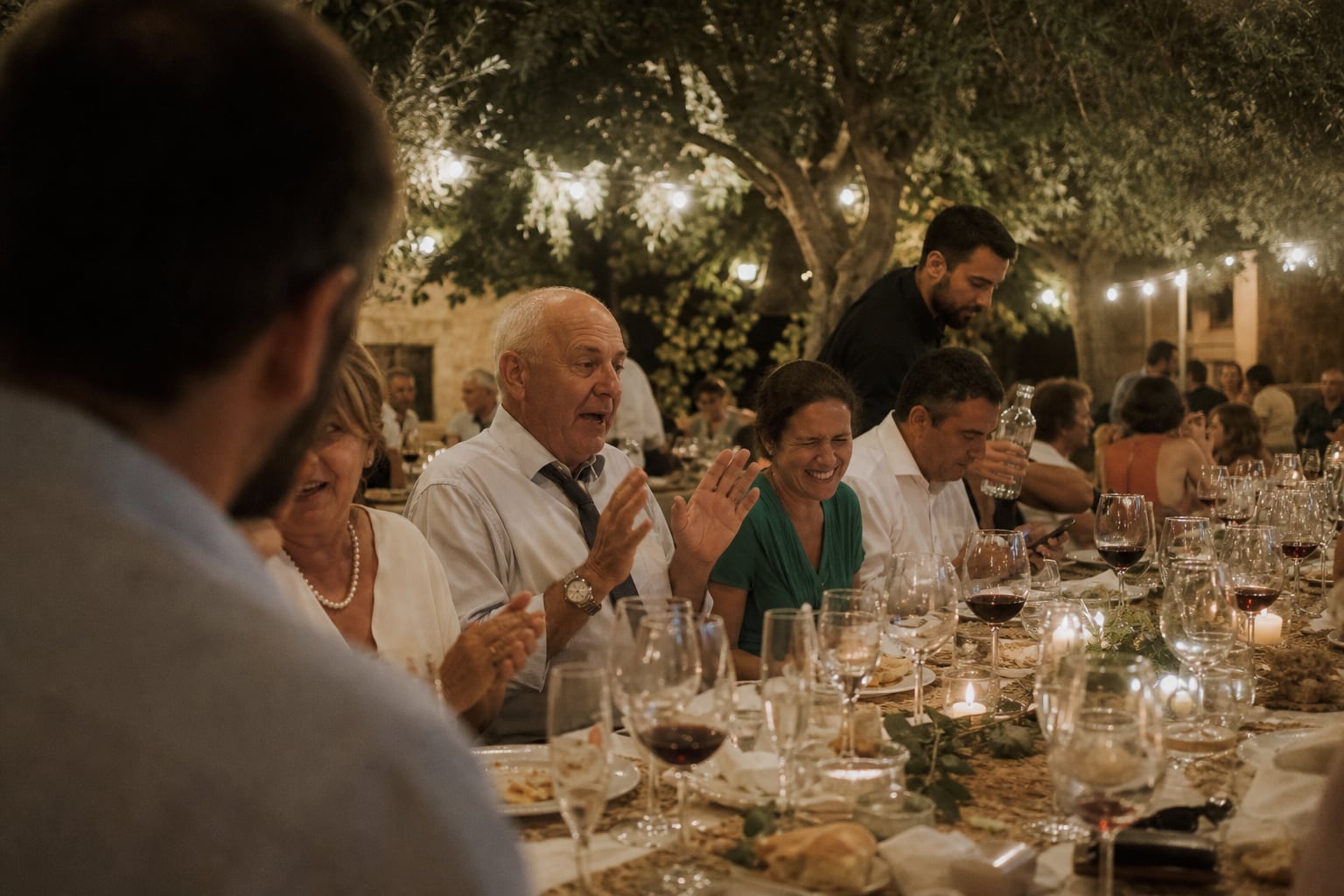 Guests laughing at a long wedding dinner under olive trees at a finca in Alicante