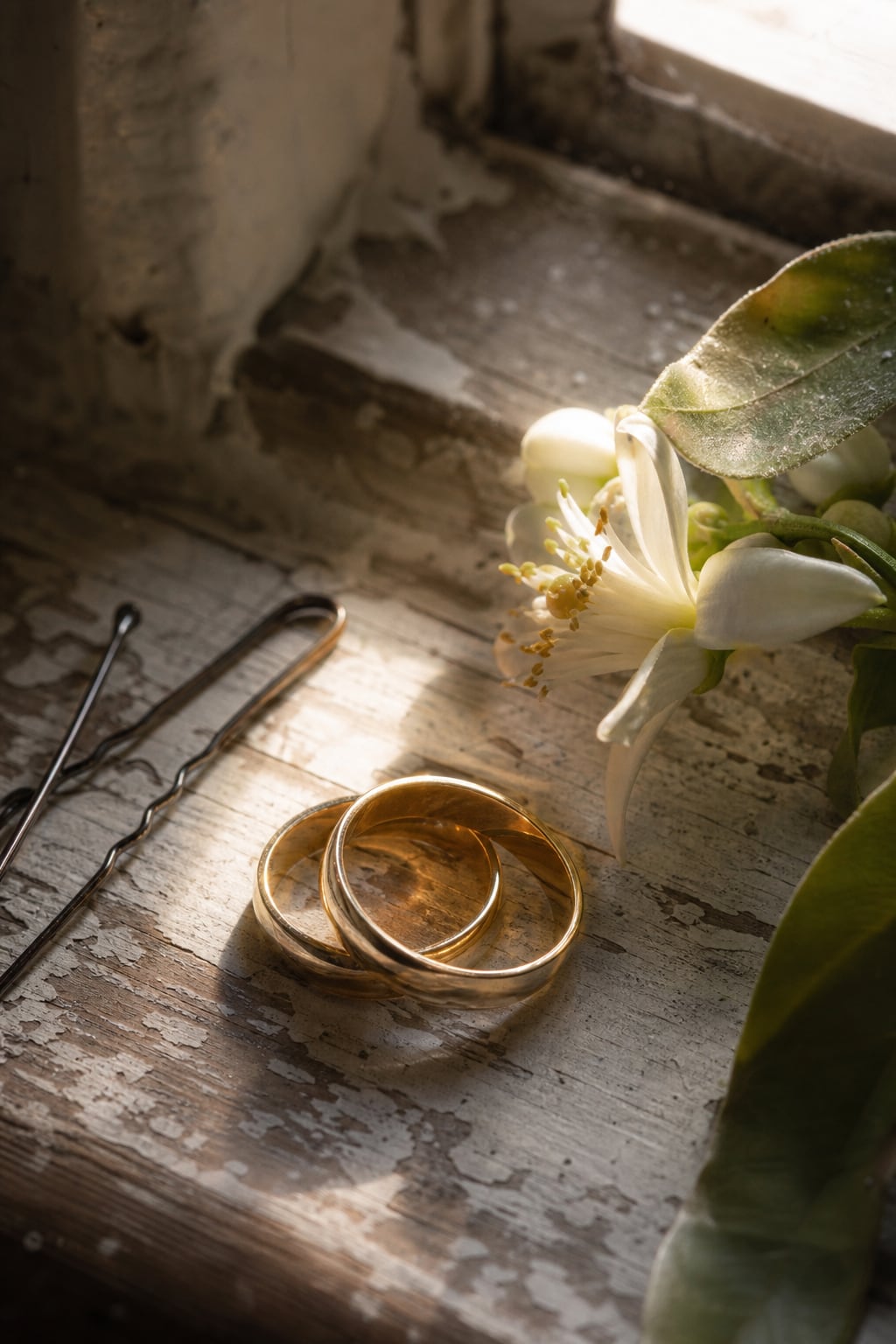 Wedding rings resting on orange blossom and a linen invitation